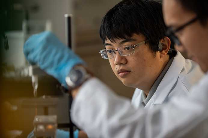 Photo of Case Western Reserve University students working in an engineering lab wearing lab coats