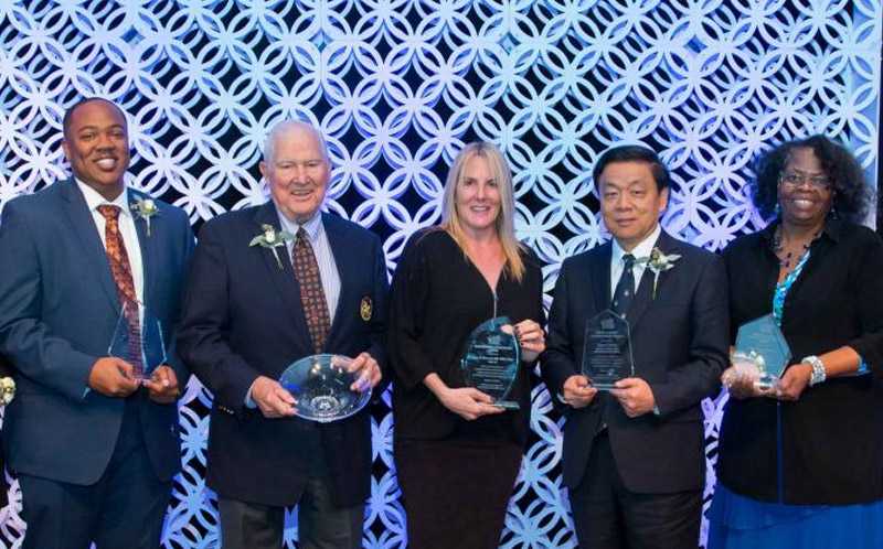 Photo of five Case Western Reserve University alumni holding crystal plaques at an award dinner