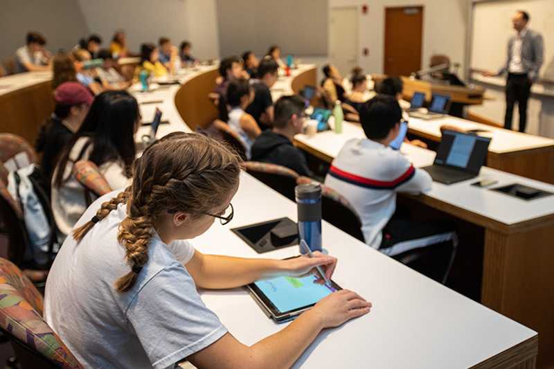 Photo of a Weatherhead School of Management classroom at Case Western Reserve University, with a focus on a student using a tablet device