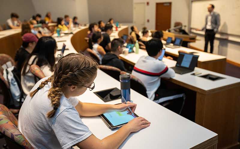 Photo of a Weatherhead School of Management classroom at Case Western Reserve University, with a focus on a student using a tablet device