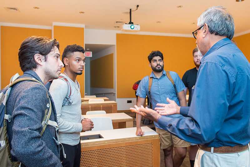 Photo of a group of Case Western Reserve University students talking with a professor in a classroom