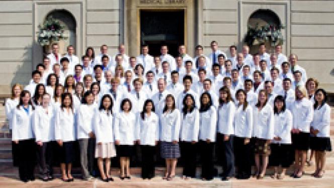 Dental students in their white coats posing for a photo