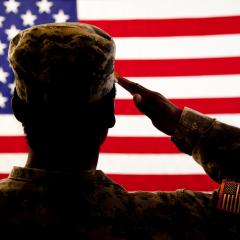 Man in military uniform saluting the American flag