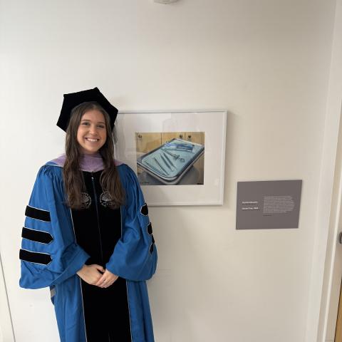 Rachel Elkowitz in cap and gown with a photo of dental instruments