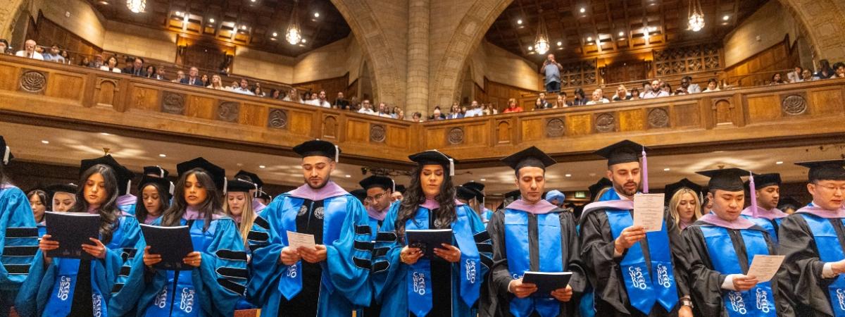 Graduates standing in auditorium on Commencement Day 2026
