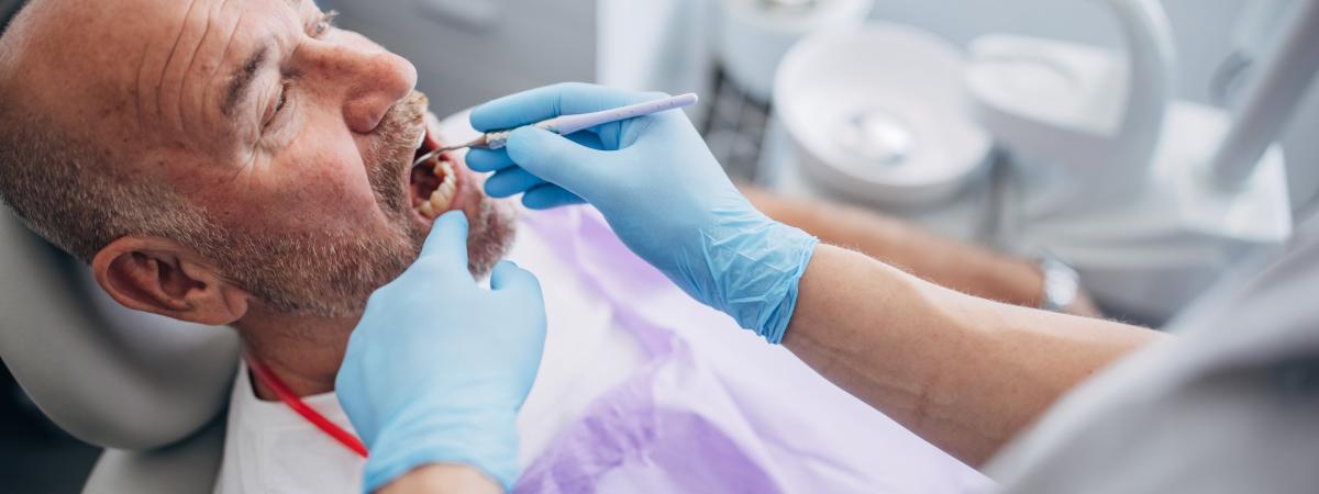 Photo of man being examined in a dental chair.