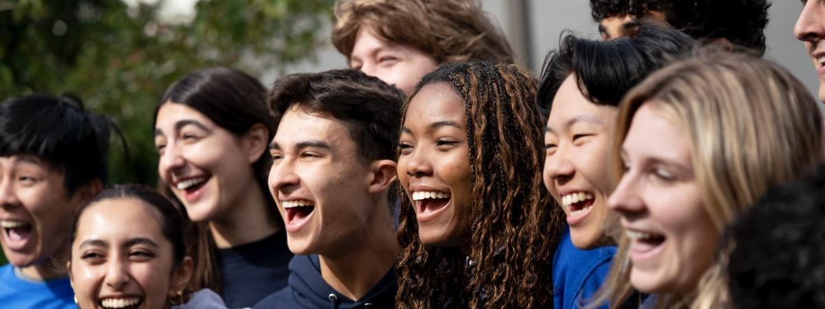 Students smile and laugh in a big group while wearing CWRU gear at homecoming.