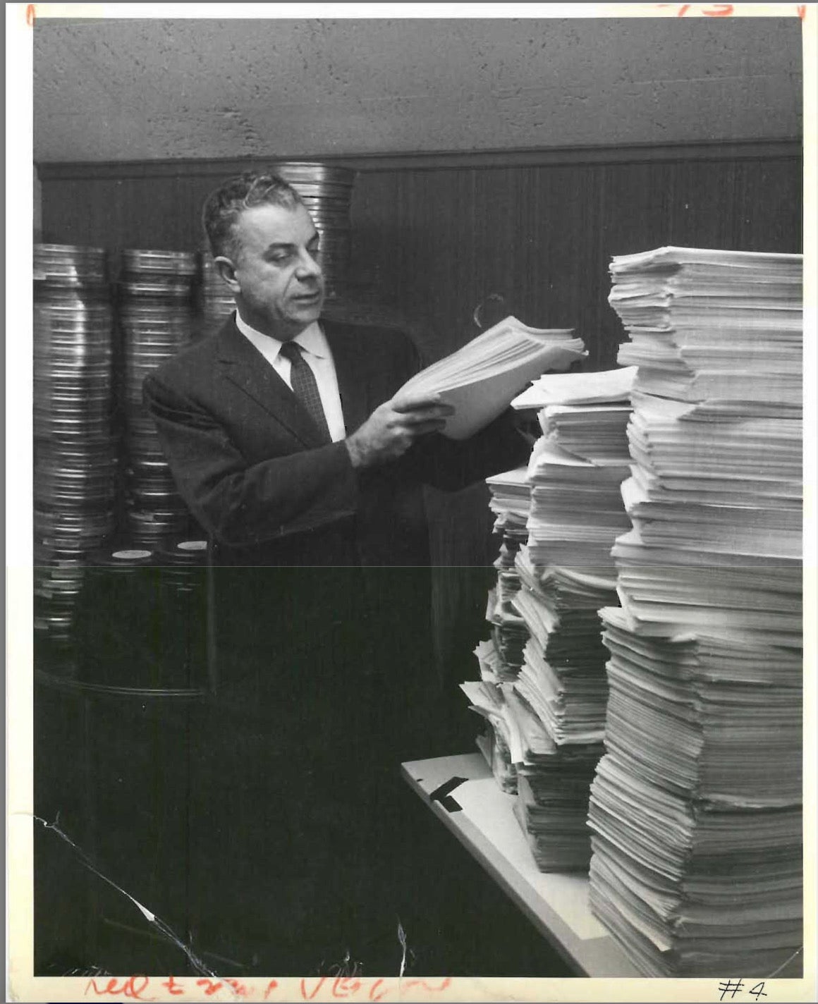 Frank Sidel standing amidst a pile of "The Ohio Story" film reels and scripts