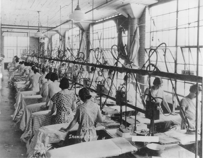 Two rows of women stand at ironing board in The Ironing Department of L.N. Gross Co. garment company, ca. 1930. WRHS.