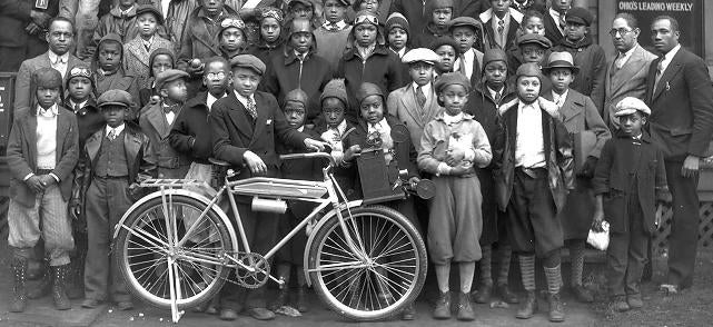 A group of newsboys with one kid holding a bike
