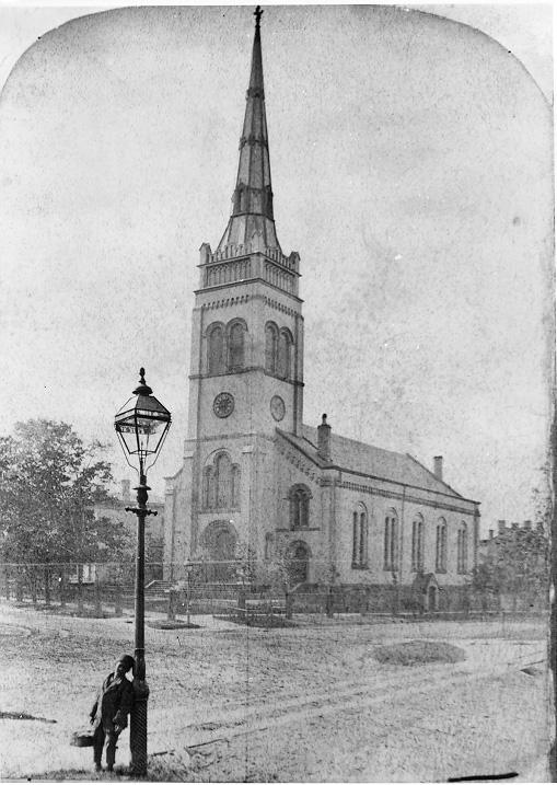 A young boy leans against a lamppost just across the street from First Baptist Church at Euclid Ave. and Erie (E. 9th) St., in 1875. WRHS.