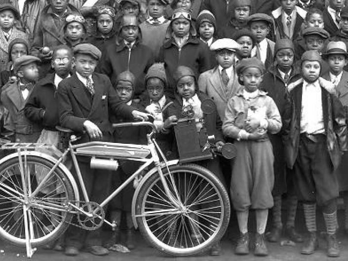 A group of newsboys with one kid holding a bike