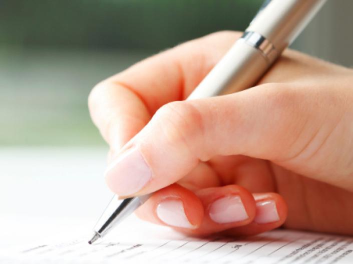 Close up of a hand writing with a pen on paper