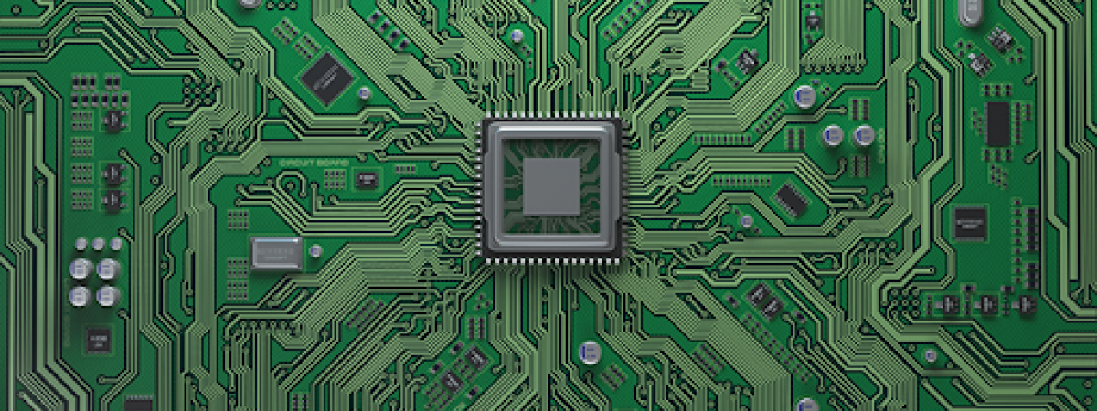 A close-up of a green circuit board with a central microchip.