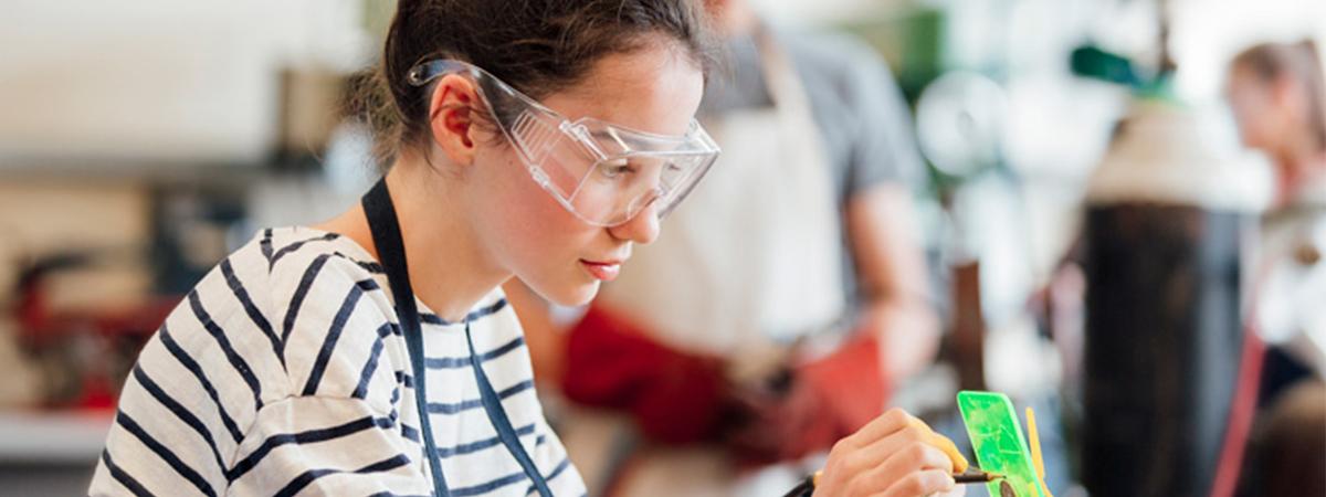 A female engineering student wearing safety glasses in a lab