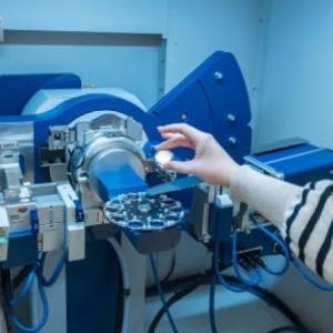 Hand holding object in front of engineering equipment
