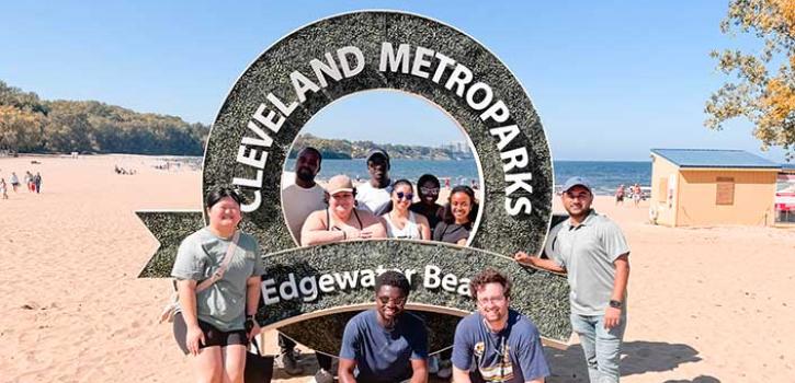 students standing on the beach in front of a metroparks sign