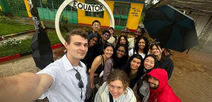 students standing in front of an equator sign
