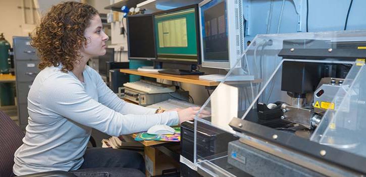 Researcher looking at a computer with a piece of equipment to the right