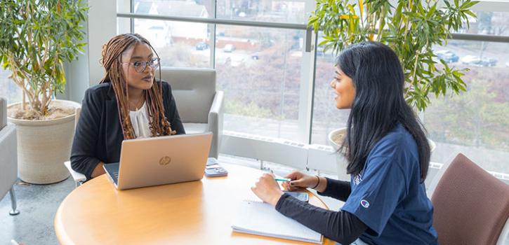 two students talking to eachother across a table
