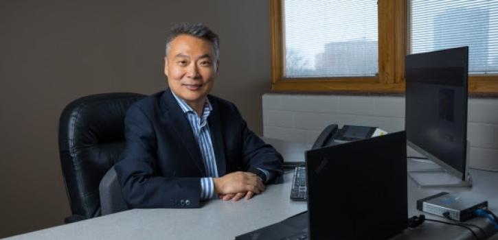 Shuo Li sitting in front of a computer