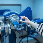 Hand holding object in front of engineering equipment