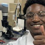 Tosa Odiase standing in front of lab equipment