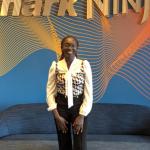 Tumi Adeeko standing in front of sign that says SharkNinja