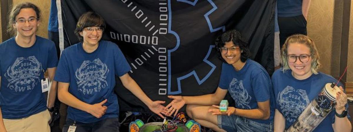 students kneeling in front of a sign with a robotics instrument