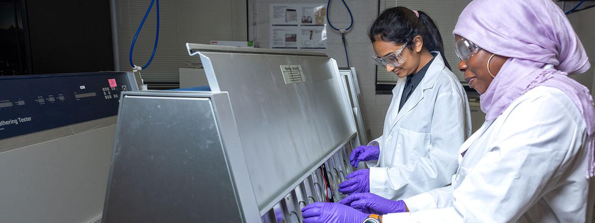 Two students with purple gloves performing a test