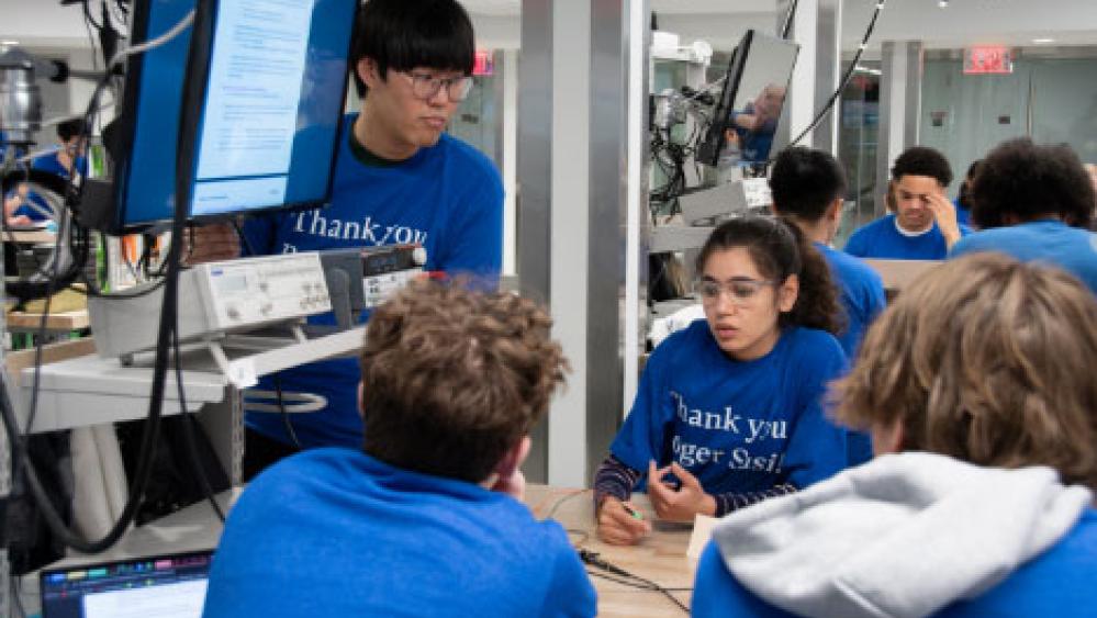 Students working together at a table with a computer screen