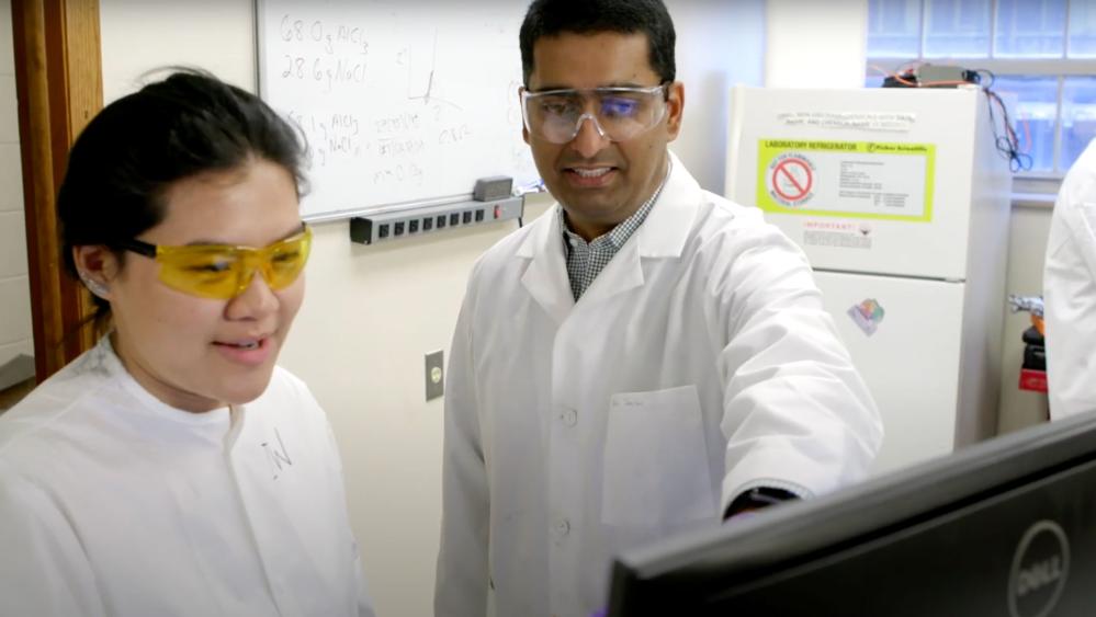 Rohan Akolkar and a student looking at a computer in the lab