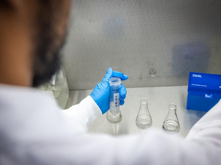 gloved hands opening a beaker
