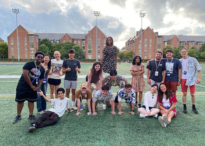 students standing on football field in front of buildings