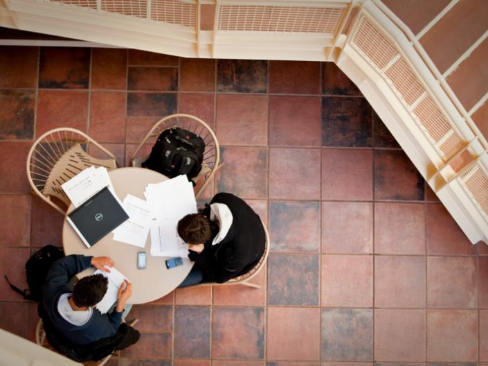 Overhead view of two people sitting at a round table looking at laptops