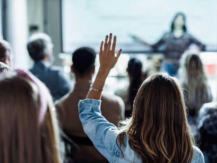 Person raising their hand in a classroom setting