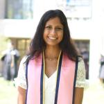 a woman smiles while wearing her pink academic stole