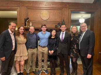 A group of smiling people standing together for a photo in front of a cozy fireplace.