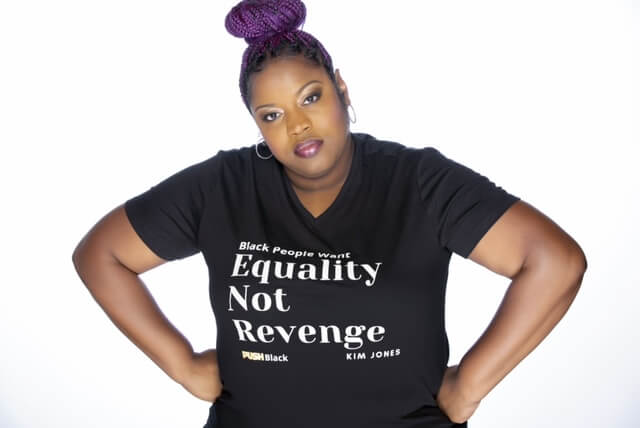 Kimberly Jones with purple hair and in a black t-shirt that reads "Equality not Revenge"