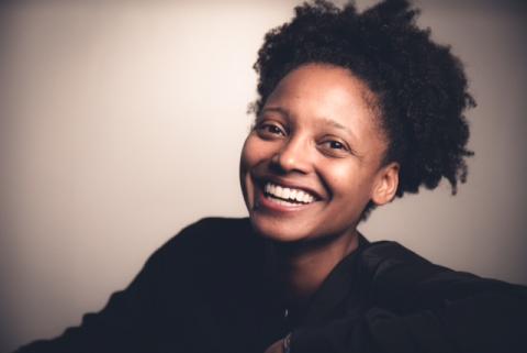 Image of poet Tracy K. Smith wearing a black shirt and smiling 