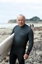Photo of Patagonia founder Yvon Chouinard with a surfboard on the beach
