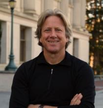 Dacher Keltner standing outside with arms crossed. 