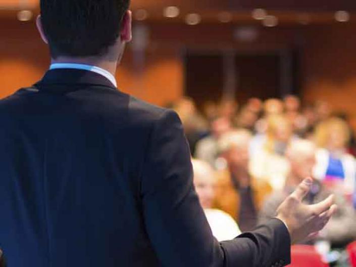 Man speaking to a crowd in a conference hall