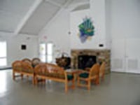 View of CWRU November Meeting Center stone fireplace, with light wood lounge chairs and white walls