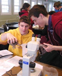 Two students working with papers and a microscope