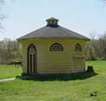 Outside view of Dovecote at CWRU Farm, a small circular structure in yellow with grey roof