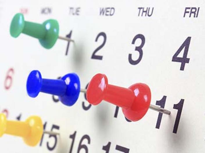Calendar showing the days of a month with colorful pushpins marking 4 days
