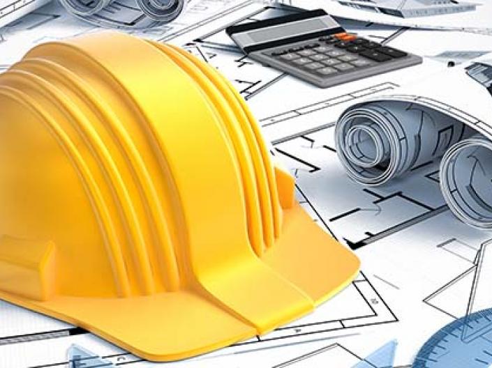 Building blueprints with a construction hat and ruler on it.
