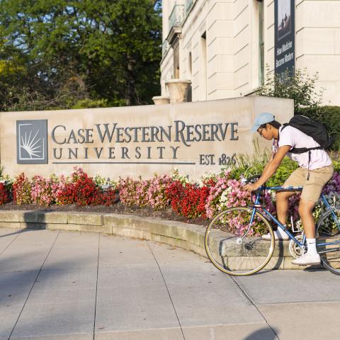 Student on bike in front of sign