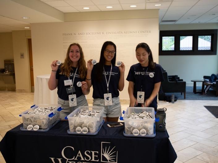three orientation leaders handing out buttons during discover week